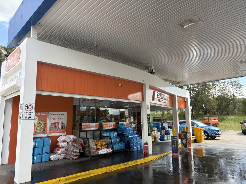 Technician pressure washing fuel forecourt at Sydney petrol station"